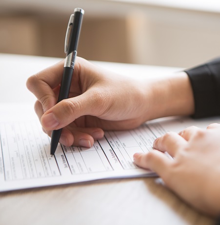Cropped View of Woman Filling in Application Form Cropped view of woman holding pen and filling in application form at table